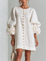 Vestido corto blanco con estampado floral, de botones frontales y puños florales llamativos.