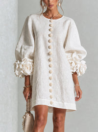 Vestido corto blanco con estampado floral, de botones frontales y puños florales llamativos.
